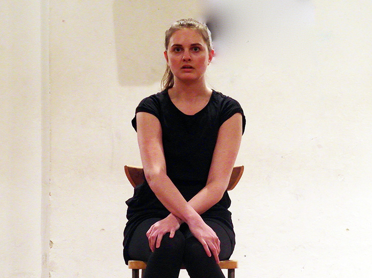 Monolog: schöne Frau sitzt mit über den Beinen gekreuzten Armen, offener, weicher Blick